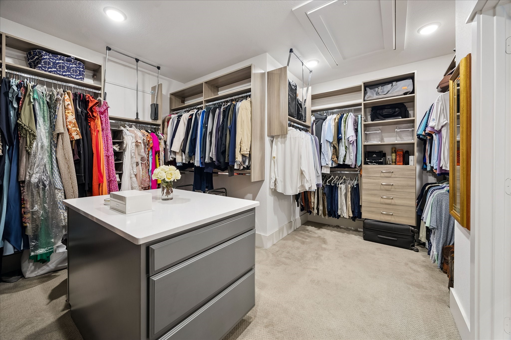 2512 Swang Pl. Houston, TX 77008 - Photo 28 of 46 This spacious walk-in closet features ample hanging space, shelving, and drawers, with a central island for additional storage. The neutral carpet and modern lighting create a bright and organized environment, perfect for managing your wardrobe.