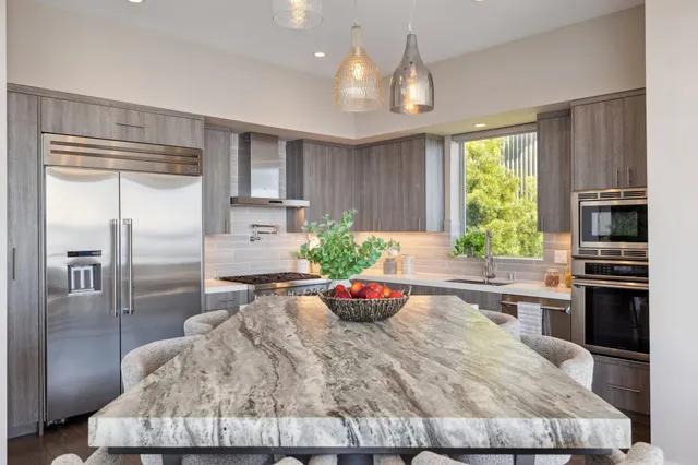 a kitchen with granite countertop kitchen island stainless steel appliances a stove refrigerator sink and cabinets