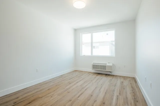 an empty room with wooden floor and windows