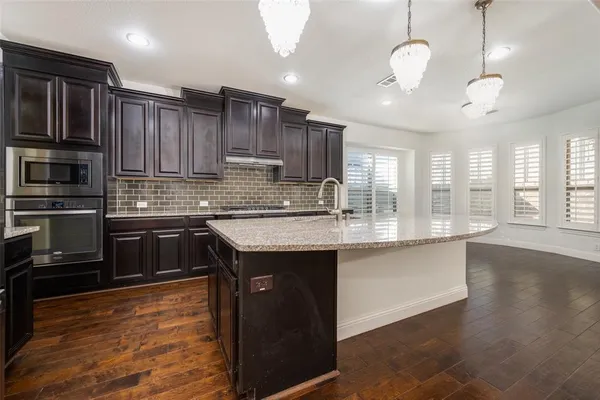 a kitchen with kitchen island granite countertop stainless steel appliances and wooden cabinets
