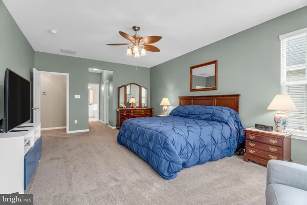 a bedroom with a bed mirror on dresser and a chandelier