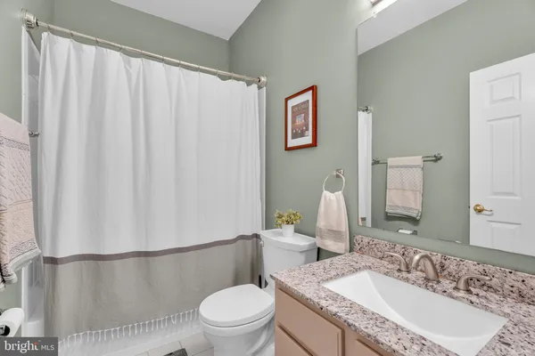 a bathroom with a granite countertop sink toilet and a mirror
