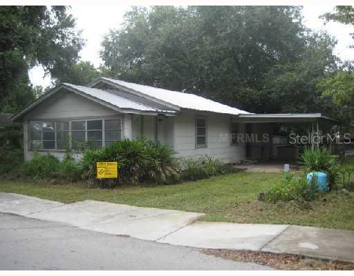 a front view of a house with a yard and potted plants