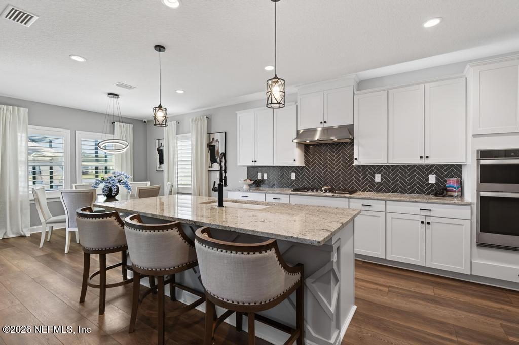 240 Ranch Land Circle St. Johns, FL 32259 - Photo 12 of 117 a kitchen with stainless steel appliances granite countertop a stove a refrigerator a kitchen island a dining table and chairs with wooden floor