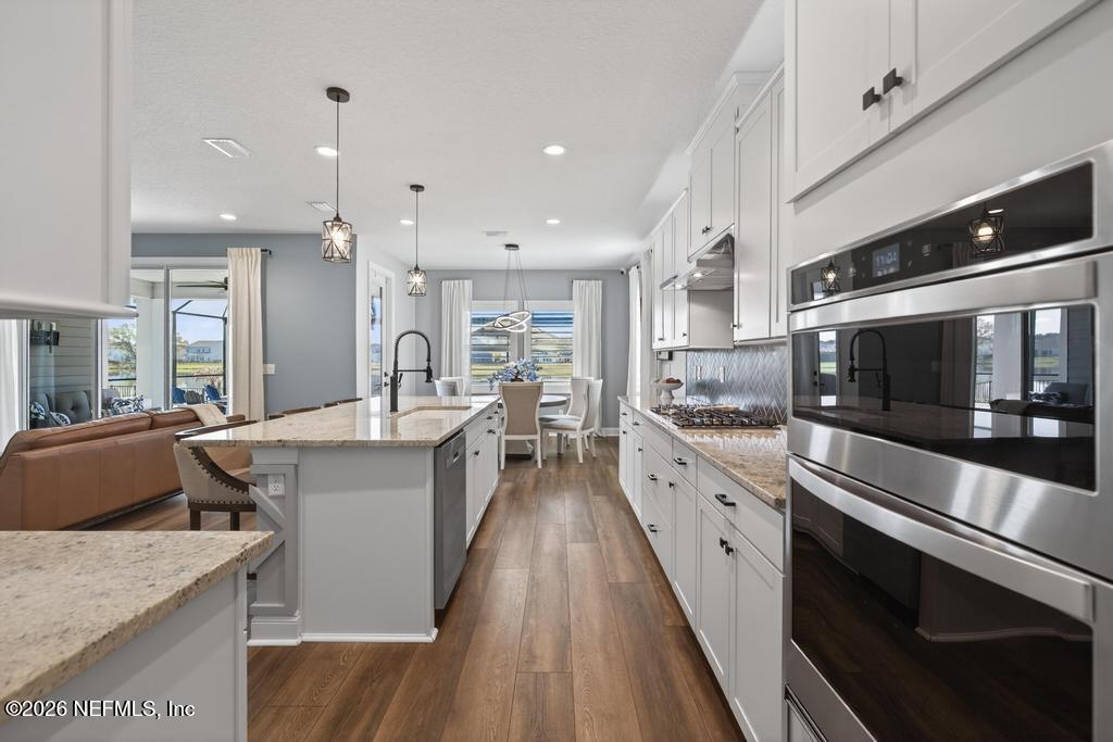 240 Ranch Land Circle St. Johns, FL 32259 - Photo 13 of 117 a large kitchen with stainless steel appliances kitchen island granite countertop a lot of counter space and wooden floor