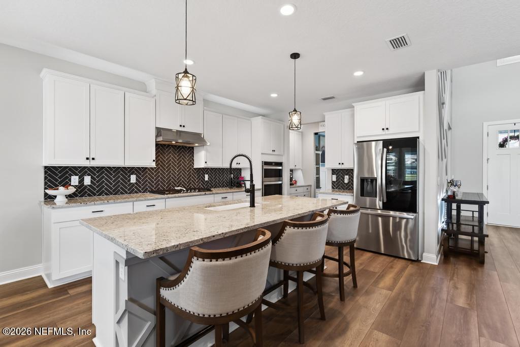 240 Ranch Land Circle St. Johns, FL 32259 - Photo 9 of 117 a kitchen with stainless steel appliances granite countertop a stove a refrigerator a kitchen island a dining table and chairs with wooden floor