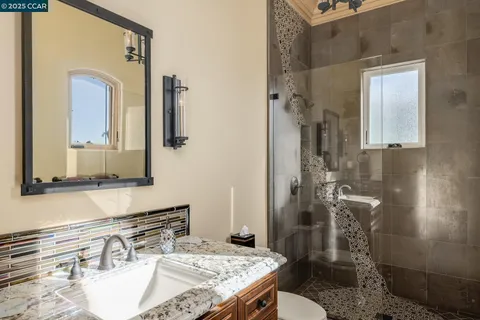 a bathroom with a granite countertop sink a mirror and shower
