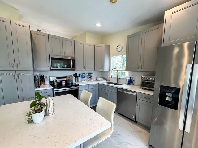 a kitchen with stainless steel appliances a white refrigerator a stove a microwave a sink and cabinets