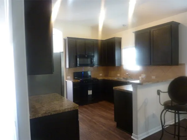 a kitchen with kitchen island granite countertop a sink cabinets and stainless steel appliances