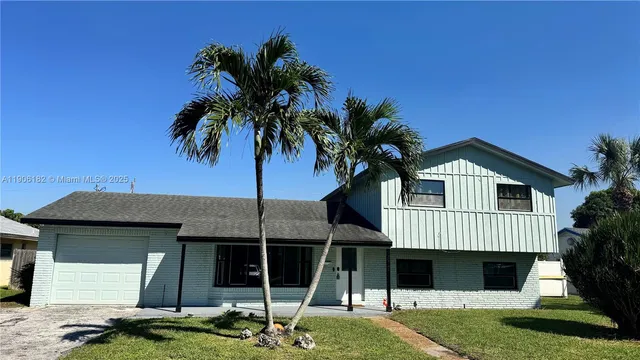a front view of a house with a garden and tree
