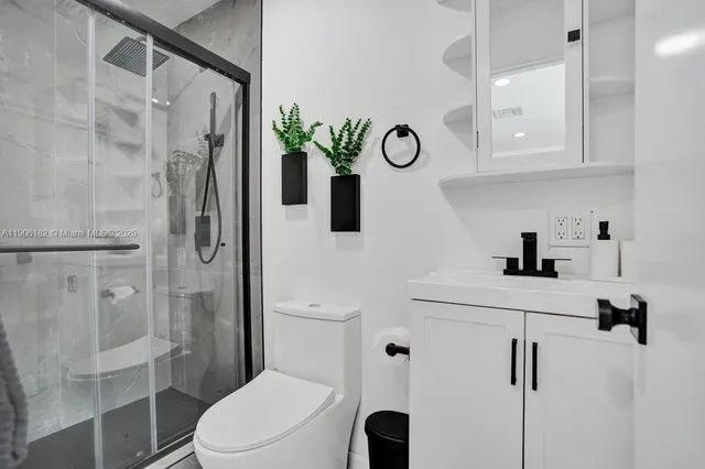 a bathroom with a sink a toilet a mirror and shower