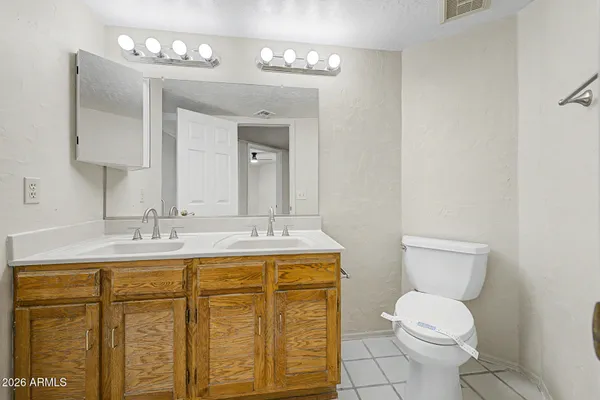 a bathroom with a granite countertop toilet sink and mirror