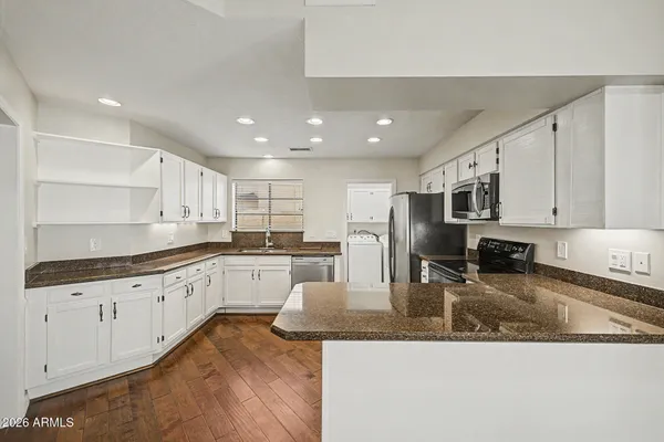 a kitchen with stainless steel appliances granite countertop a sink refrigerator and cabinets