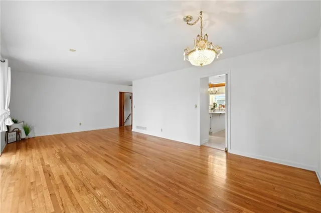 a view of an empty room with wooden floor and window