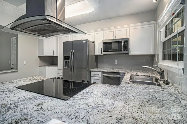 a kitchen with stainless steel appliances granite countertop a sink a microwave a stove and refrigerator