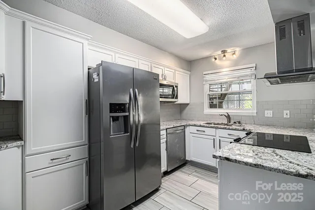 a kitchen with stainless steel appliances granite countertop a refrigerator and a sink