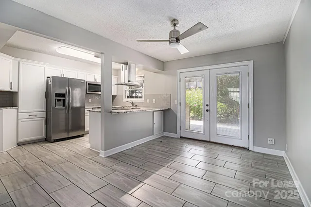 a view of kitchen with stainless steel appliances granite countertop a refrigerator and microwave