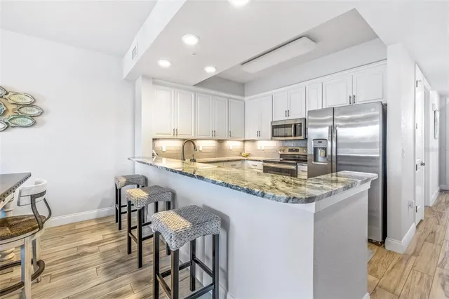 a kitchen with kitchen island granite countertop a sink and a white cabinets
