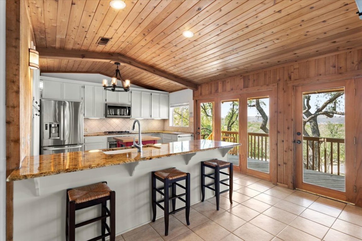16808 Forest Way Austin, TX 78734 - Photo 12 of 33 a dining hall with stainless steel appliances granite countertop a stove kitchen island a table and chairs with wooden floor