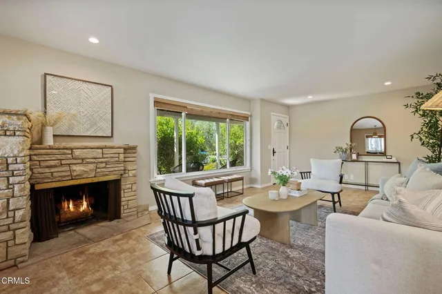 a living room with furniture a fireplace and a large window