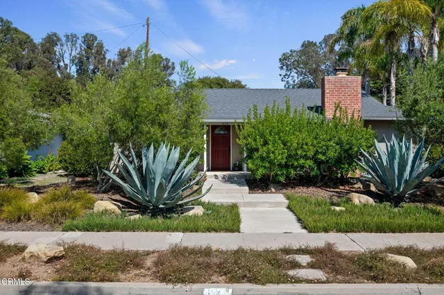 a front view of a house with a garden and plants