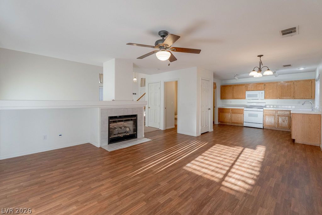 8379 Rockefeller Street Las Vegas, NV 89123 - Photo 8 of 36 Rich wood floors seamlessly connect a cozy fireplace-accented living area to the adjacent kitchen.