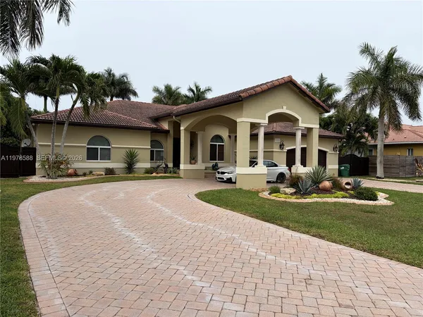 a front view of a house with a yard and palm trees