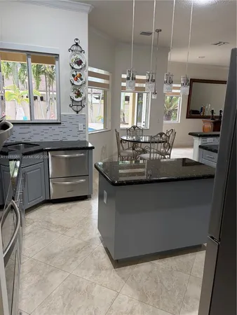 a kitchen with kitchen island granite countertop a sink cabinets and window