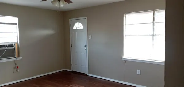 an empty room with wooden floor closet and windows