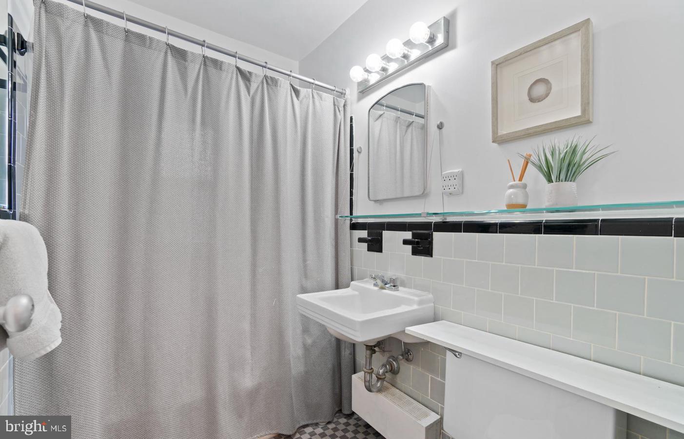 4100 W Street Northwest, Unit 410 Washington, DC 20007 - Photo 8 of 17 a bathroom with a sink a mirror and a shower curtain