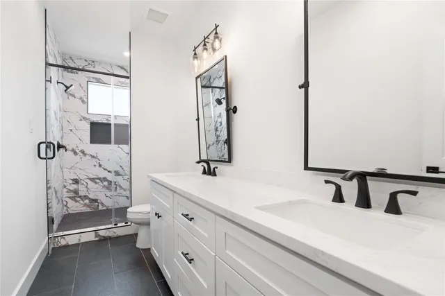 a bathroom with a double vanity sink mirror and shower