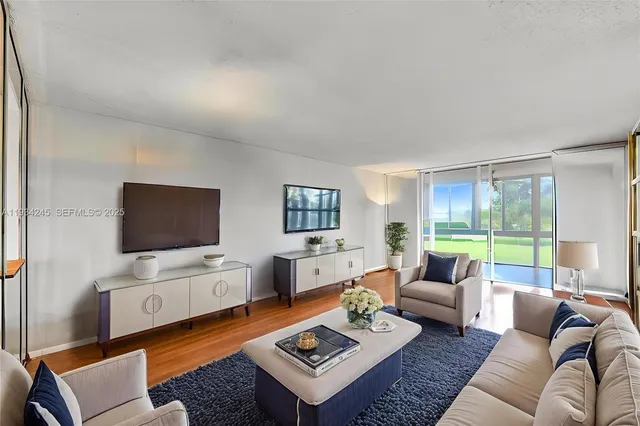 a living room with furniture a flat screen tv and a floor to ceiling window