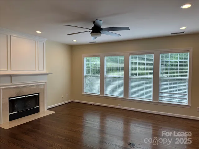 a view of an empty room with wooden floor fireplace and a window