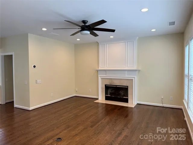 a view of an empty room with wooden floor fireplace and a window