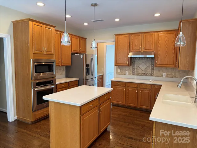 a kitchen with stainless steel appliances granite countertop a sink a stove and a refrigerator