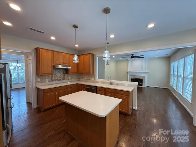 a kitchen with a sink a counter top space stainless steel appliances and wooden floor