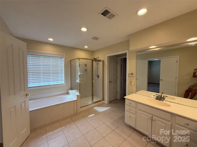 a bathroom with a double vanity sink large mirror and a bathtub