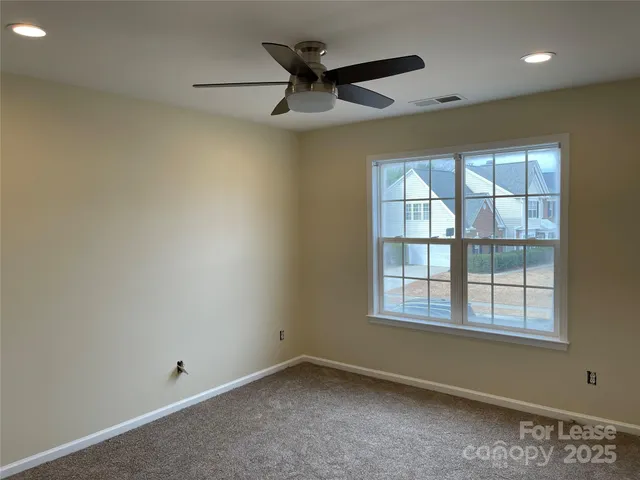 an empty room with ceiling fan and windows