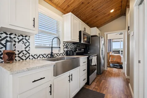 a kitchen with granite countertop white cabinets and stainless steel appliances