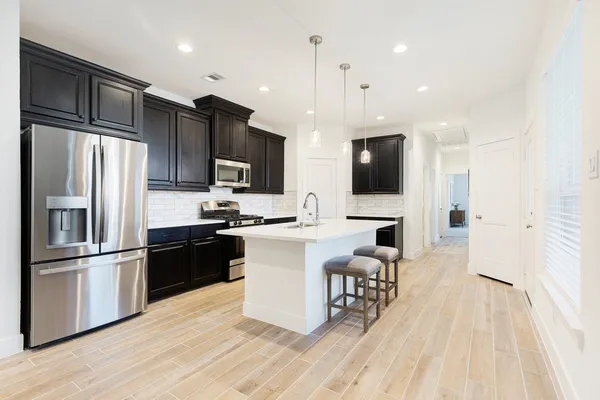 a white kitchen with wooden floor stainless steel appliances and cabinets