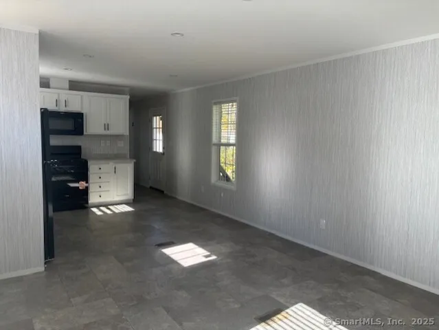a view of an empty room with a kitchen and a window