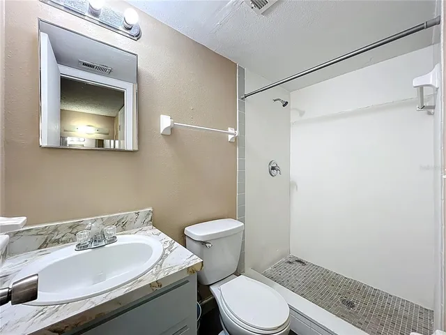a bathroom with a granite countertop toilet sink and mirror
