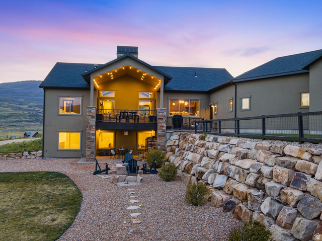 402 Shadow Hill Road Wanship, UT 84017 - Photo 1 of 90 Back of house at dusk with a patio, stucco siding, a fire pit, a shingled roof, and a balcony