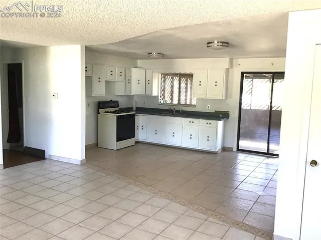 a kitchen with granite countertop a stove a sink and a refrigerator