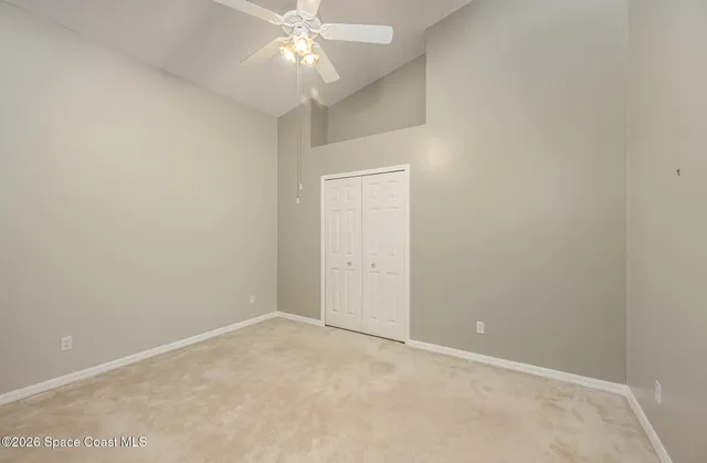 an empty room with a chandelier fan and closet