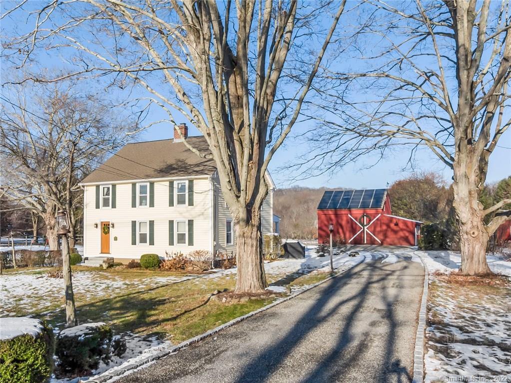 a view of a white house with a yard covered in the forest