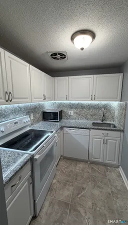 a kitchen with granite countertop a sink and cabinets