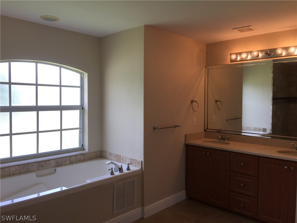 4015 36th Street Southwest Lehigh Acres, FL 33976 - Photo 10 of 23 a bathroom with a tub a sink and a window