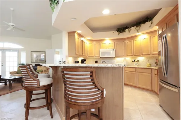 a kitchen with a sink dishwasher a stove a refrigerator with island and chairs