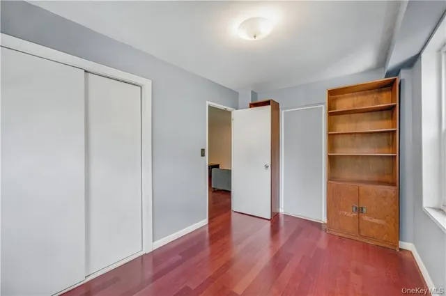 a view of an empty room with closet and wooden floor